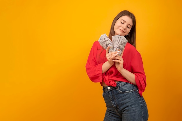 Teenage girl holds wad of us dollars and smiles successful youth young business woman rich and carefree concept copy space