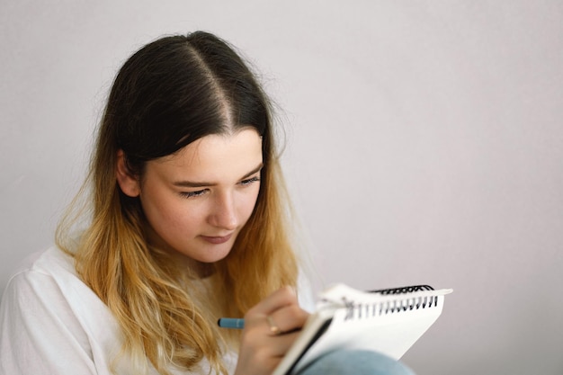 Foto un'adolescente disegna o fa i compiti in camera da letto un'adolescente studia a casa ritorno a scuola
