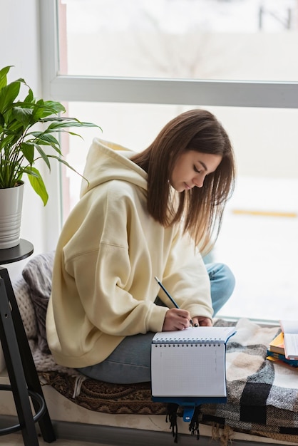 10代の少女が自宅で遠隔地で試験の準備をしているホームスクーリング教育ソフトセレクティブフォーカス