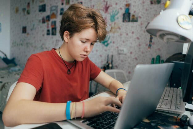 Photo a teenage girl is studying online using a laptop while sitting at a table in the room