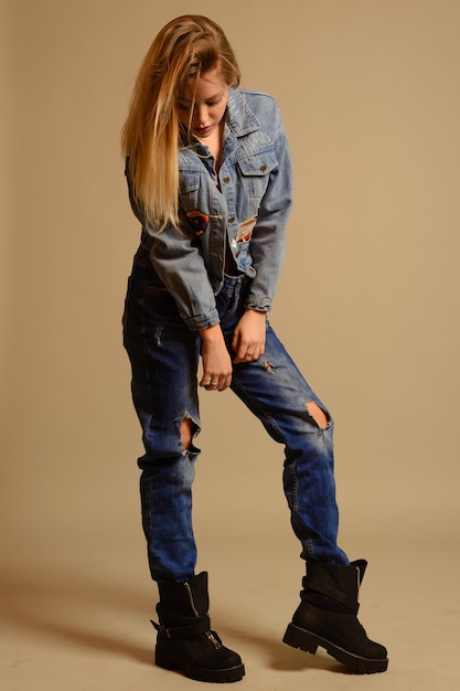 Photo teenage girl in jeans stands looking down on gray