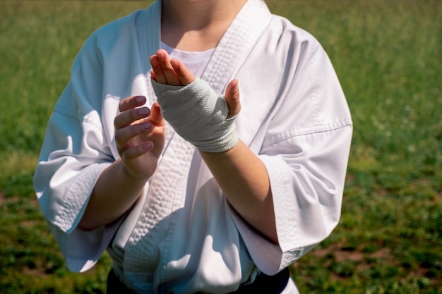 Teenage girl in a kimono wrapping a wrist wrap before starting outdoor karate training