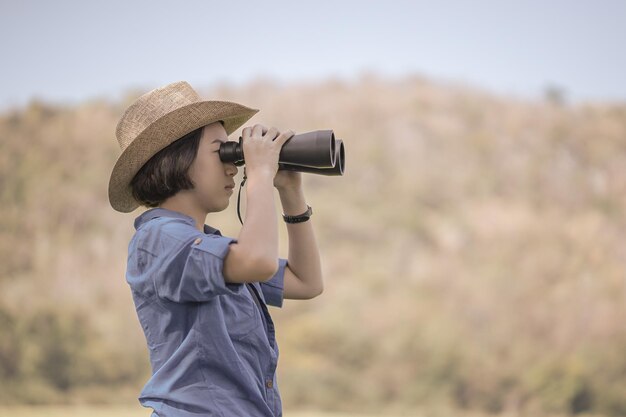 写真 公園で双眼鏡を通して見ているティーンエイジャーの女の子