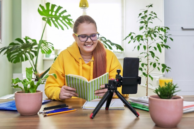 オンラインレッスンのためにスマートフォンを使用してウェブカメラを見ている10代の少女