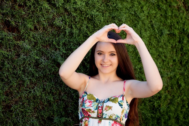 Teenage girl in love making a heart with her hand
