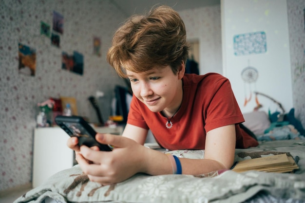 Teenage girl lying on the bed writes messages on the phone