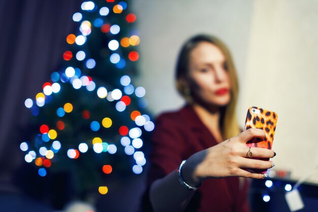 Adolescente che fa selfie vicino all'albero di natale a casa