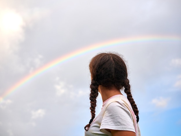 Teenage girl outdoors looking at the rainbow