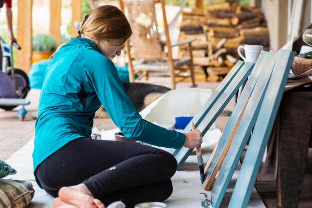 Teenage girl painting wooden shelves blue