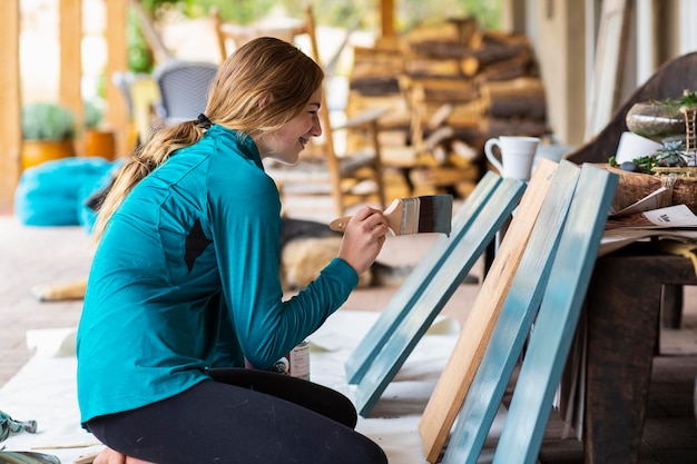 Teenage girl painting wooden shelves blue