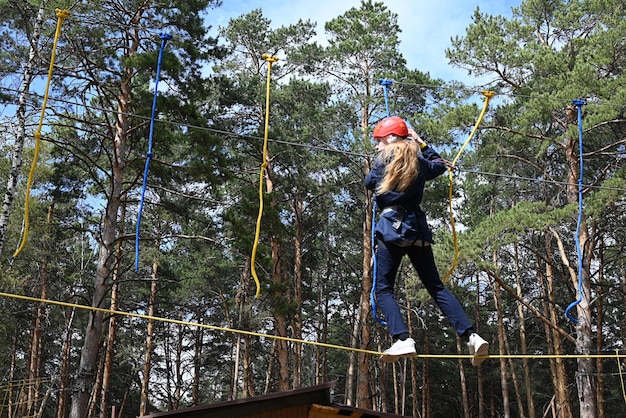 a teenage girl passes an obstacle in a rope park