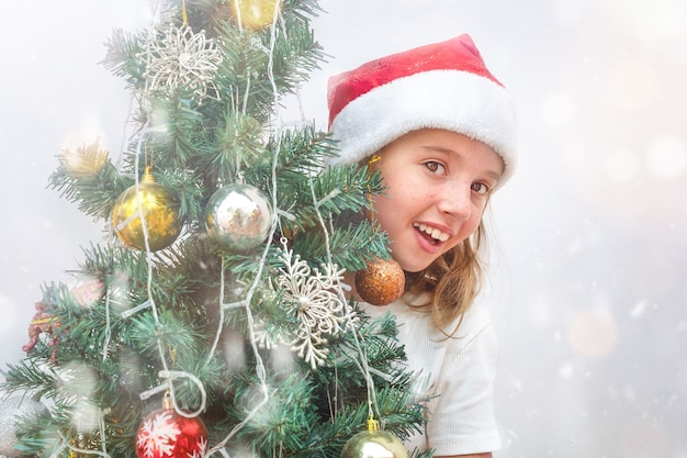 Teenage girl peeking out from behind a busy christmas tree