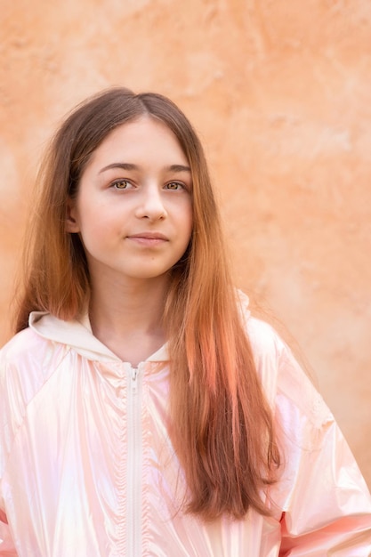 Photo a teenage girl in a pink jacket on a beige background portrait of a beautiful girl