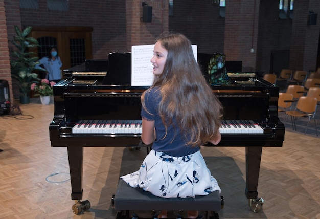 Teenage girl playing the piano in the concert hall hobby music