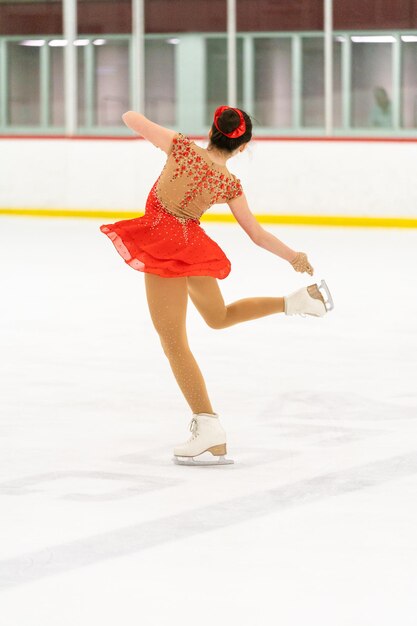 Photo teenage girl practicing figure skating on an indoor ice skating rink.