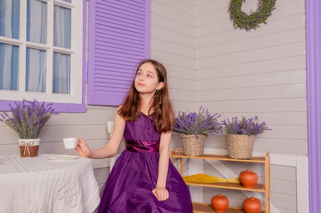 Teenage girl in a purple dress indoors. A girl with blond hair in a beautiful dress. teenager, girl