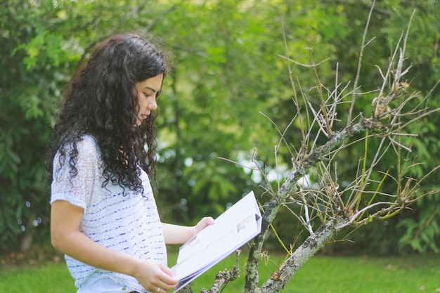 Foto ragazza adolescente che legge un libro al parco