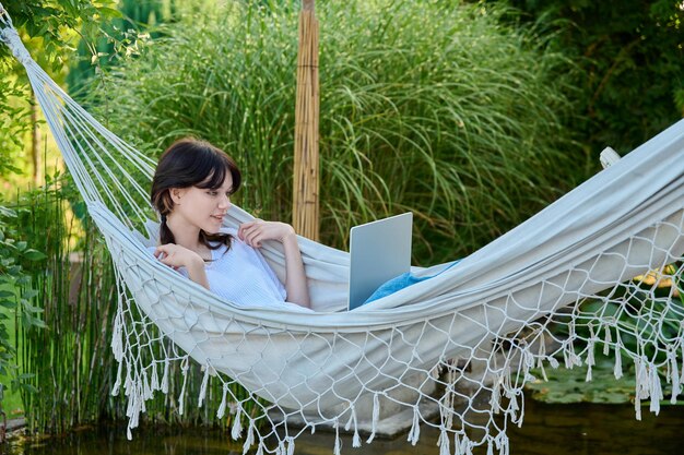 레저 연구를 위해 노트북을 사용하여 해먹에서 휴식을 취하는 십대 소녀