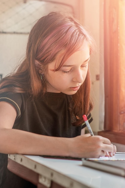 A teenage girl rides a train The girl writes with a pencil in a notebook