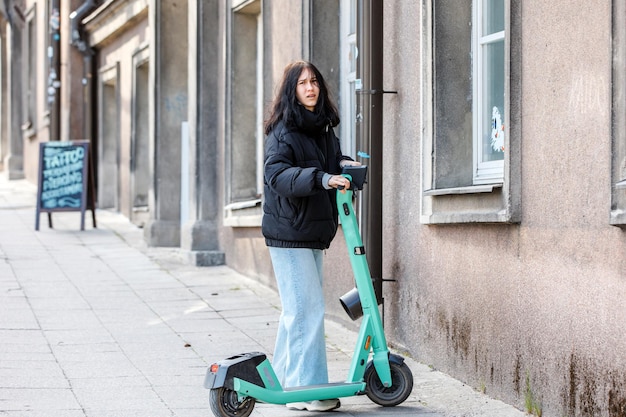 Teenage girl riding scooter on pavement