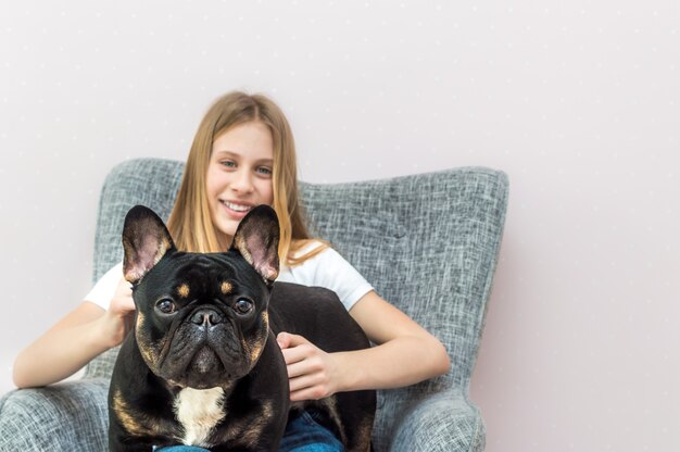 Photo teenage girl sitting in a chair at home with her french bulldog dog in her arms