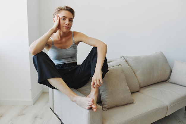 Teenage girl sitting on the couch at home smiling in home clothes and glasses with a short haircut lifestyle without filters free copy space