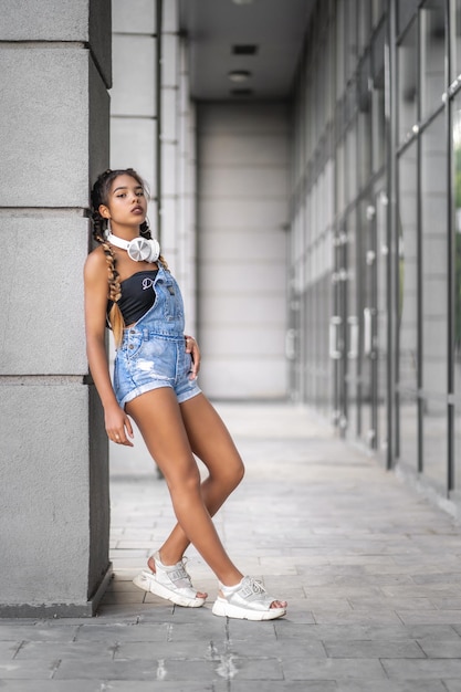 A teenage girl standing against wall and waiting for somebody