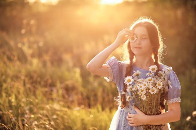 10 代の少女がヒナギクの花束を持って立っています。