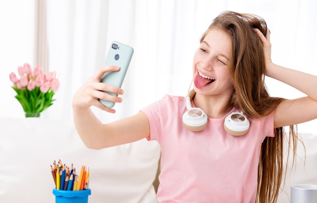 Teenage girl taking a selfie while wearing headphones