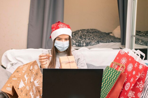 A teenage girl talks to her family online via video link shows gifts and wishes them a merry Christmas and a happy new year with a glass of champagne