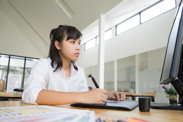 写真 テーブルの上でデスクトップコンピュータを使っているティーンエイジャーの女の子