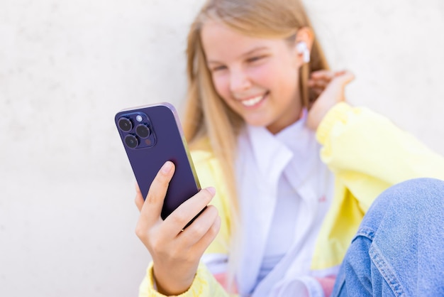 Teenage girl using mobile phone and listening to music on\
wireless earbuds