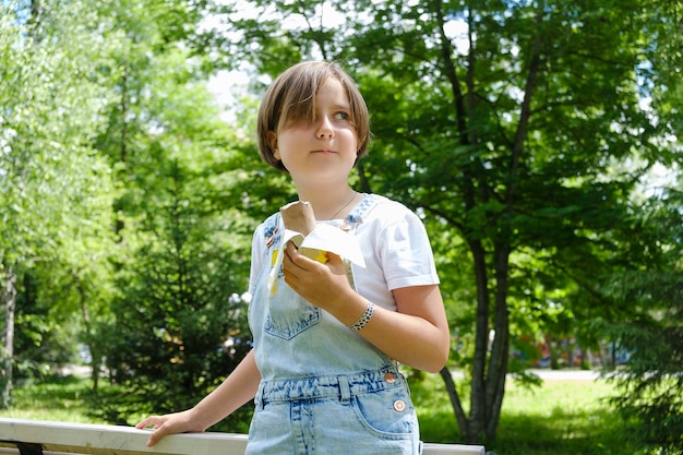 アイスクリームを楽しむために公園で夏の日に散歩している10代の少女