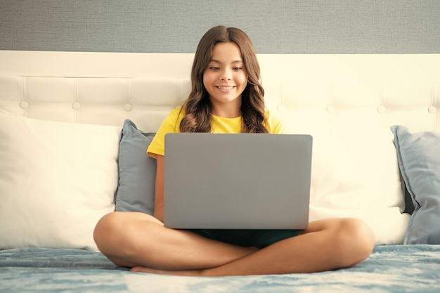 십대 소녀는 노트북에서 TV 영화를 보고 침대에 누워있으며 십대는 온라인에서 비디오 컨퍼런스 통화를합니다.