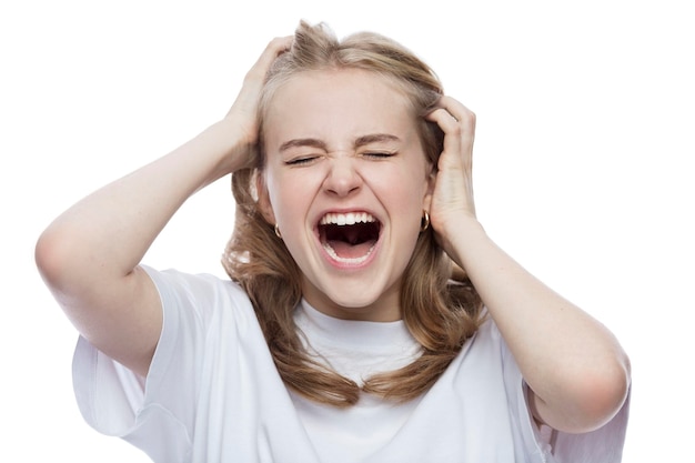 Photo a teenage girl in a white tshirt emotionally screams and holds her head with her hands stress and negativity isolated on white background closeup