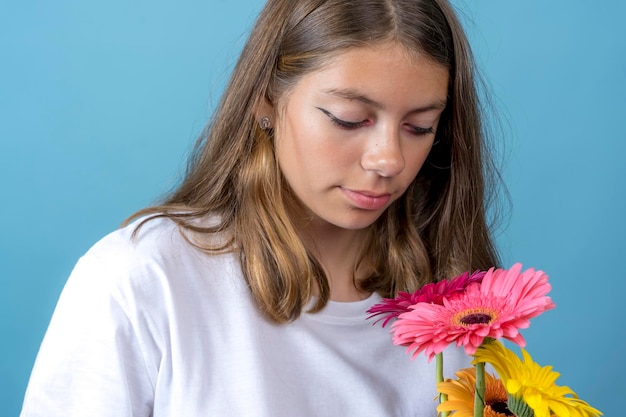 手に持ったガーベラの花を見つめる 10 代の少女