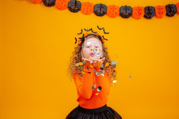 Teenage girl in a witch costume on a yellow background halloween