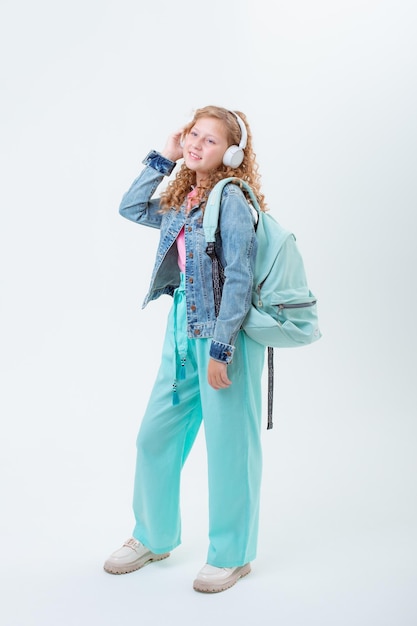 A teenage girl with a backpack in headphones on a white background