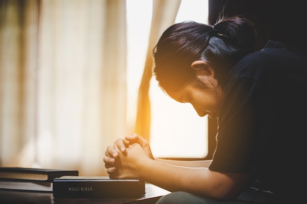 Foto adolescente con la bibbia che prega al mattino.