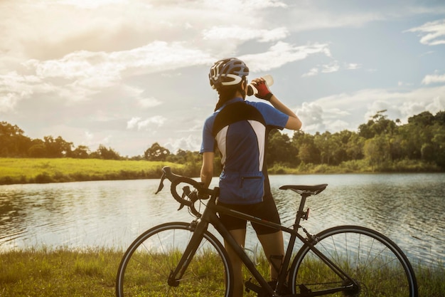 teenage girl with bicycle standing at lakeshore