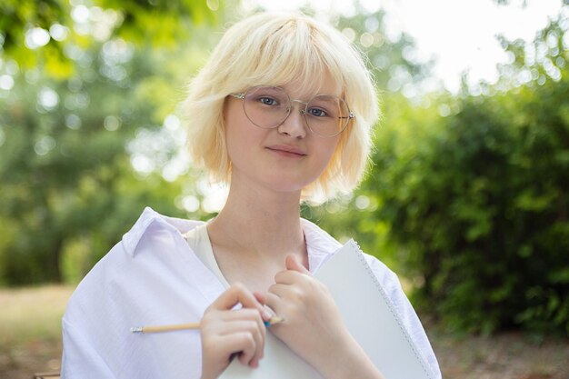 Foto ragazza adolescente con un libro di carta vuoto all'aperto ritratto in primo piano