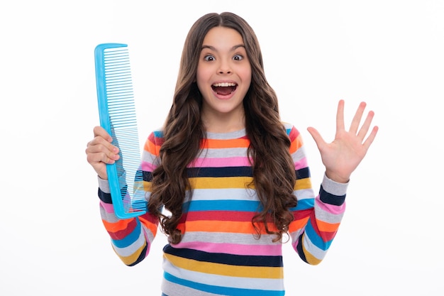 Teenage girl with brush combing hair girl taking hairstyle\
child brushing hair with comb kids haircare excited face cheerful\
emotions of teenager girl