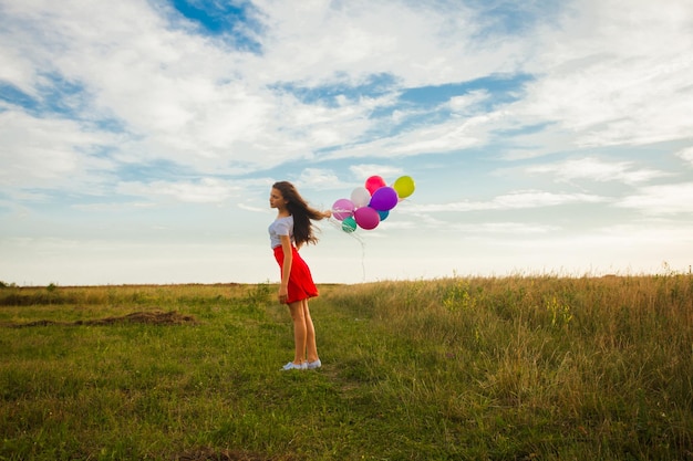 L'adolescente con palloncini colorati si trova sul prato, luogo per testo o citazione ispiratrice