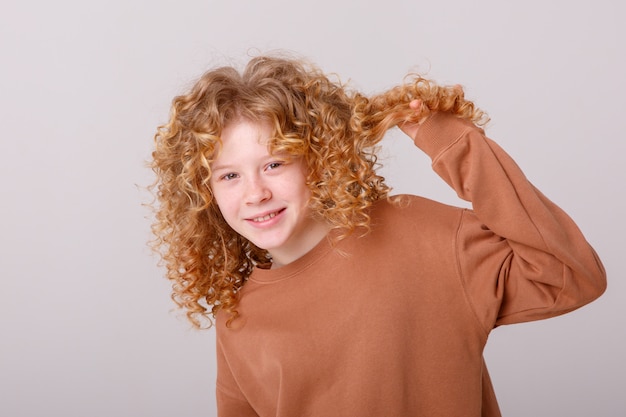 a teenage girl with curly hair is smiling   dabbles on a white background