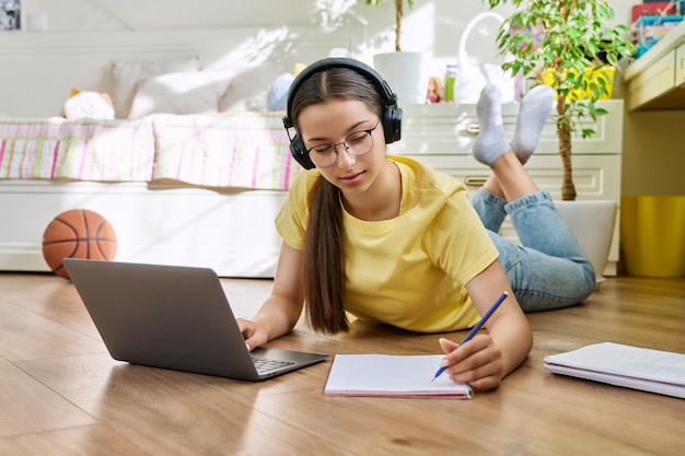 Teenage girl with glasses studying at home using a laptop