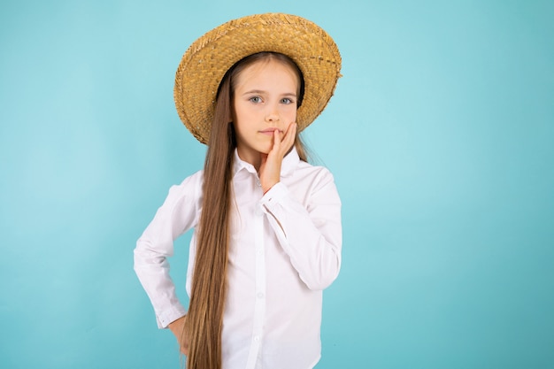 A teenage girl with grey eyes, nice smile and with a hat isolated on blue 