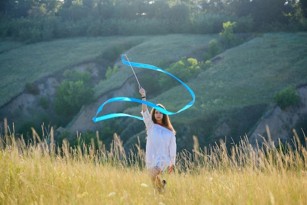 A teenage girl with a gymnastic ribbon on a hillside