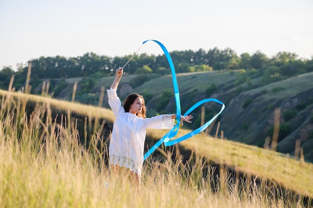 A teenage girl with a gymnastic ribbon on a hillside