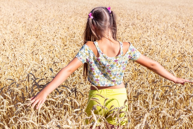 Teenage girl with outstretched hands in a wheat field