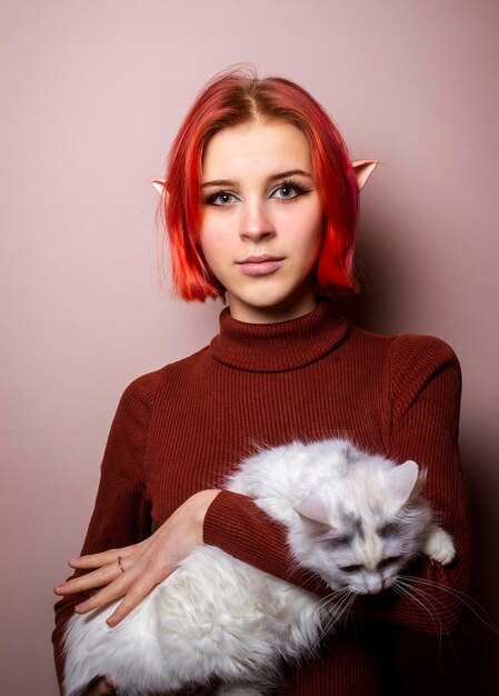 Teenage girl with pink hair holding a white cat in her arms